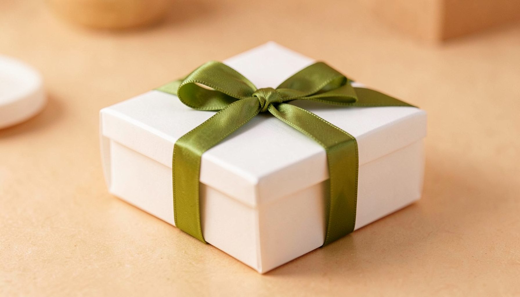 Kleines olivgrünes Geschenkband um eine schlichte weiße Box