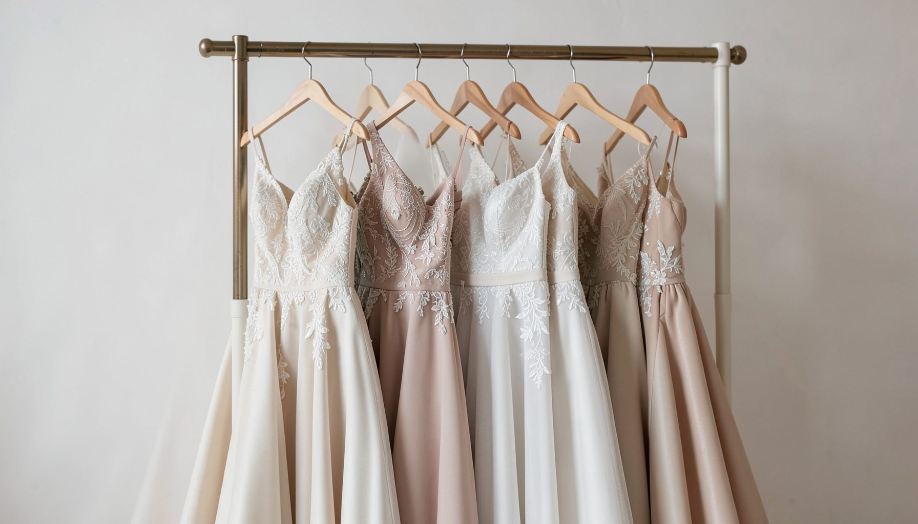 Elegante Brautkleider auf einer Kleiderstange, neutrale Farben, sanftes Studiolicht